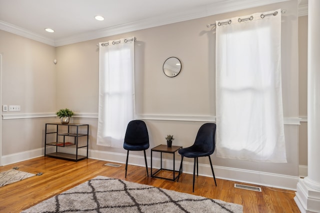 sitting room with ornate columns, crown molding, and wood-type flooring