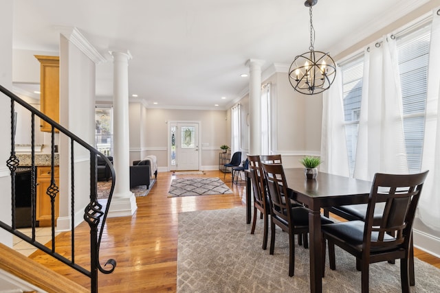 dining area with a chandelier, crown molding, decorative columns, and wood-type flooring