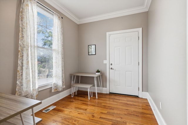 foyer entrance with a wealth of natural light, light hardwood / wood-style floors, and ornamental molding