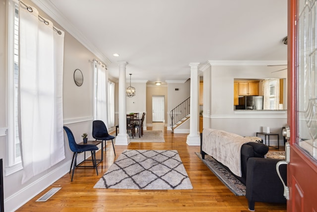 living room featuring an inviting chandelier, light hardwood / wood-style floors, and ornamental molding