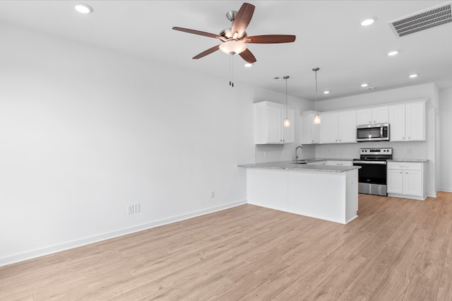 kitchen featuring light wood-type flooring, sink, kitchen peninsula, appliances with stainless steel finishes, and white cabinetry