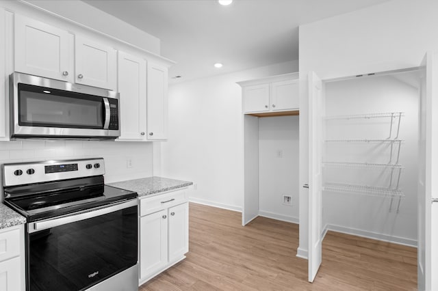 kitchen with light stone countertops, appliances with stainless steel finishes, and white cabinetry