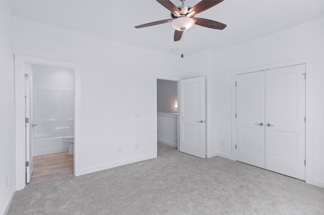 unfurnished bedroom with light carpet, a closet, connected bathroom, and ceiling fan