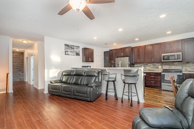 living room with ceiling fan, a textured ceiling, and dark hardwood / wood-style floors