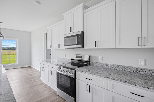 kitchen with light stone counters, pendant lighting, light hardwood / wood-style flooring, white cabinetry, and stainless steel appliances