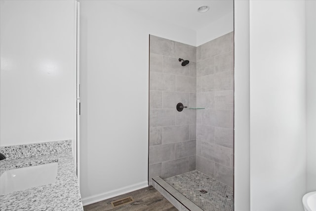 bathroom featuring a tile shower, hardwood / wood-style flooring, toilet, and sink