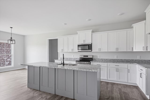 kitchen featuring white cabinets, sink, a kitchen island with sink, stainless steel appliances, and light stone countertops