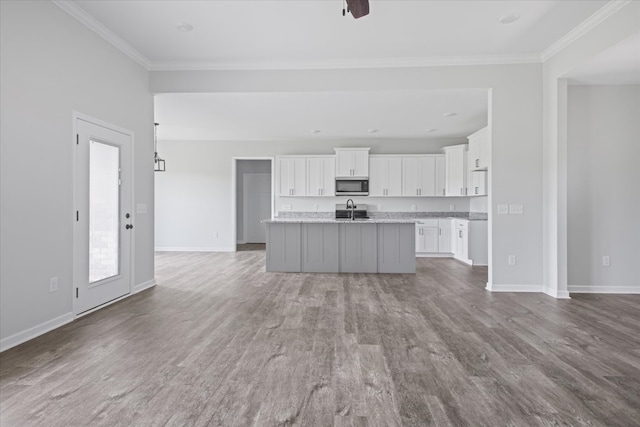 kitchen featuring an island with sink, white cabinets, hardwood / wood-style flooring, sink, and ornamental molding