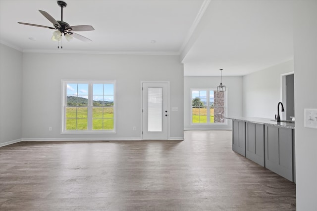 unfurnished living room featuring ceiling fan, ornamental molding, hardwood / wood-style flooring, and sink