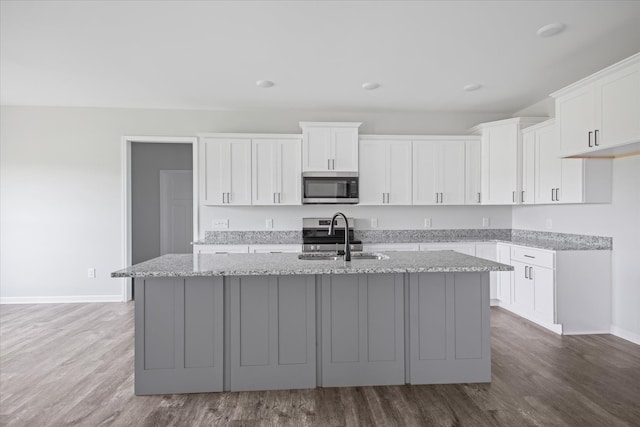 kitchen with an island with sink, sink, dark wood-type flooring, white cabinetry, and stainless steel appliances