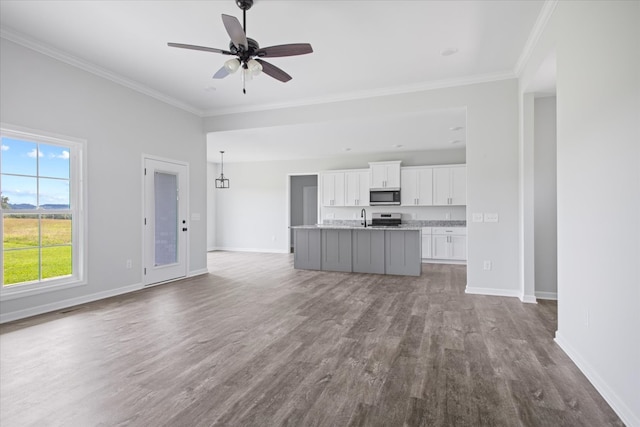 unfurnished living room featuring wood-type flooring, sink, ornamental molding, and ceiling fan