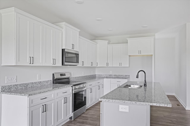 kitchen with dark wood-type flooring, a center island with sink, sink, white cabinets, and appliances with stainless steel finishes