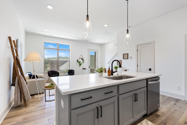 kitchen featuring gray cabinetry, sink, pendant lighting, light hardwood / wood-style flooring, and a center island with sink