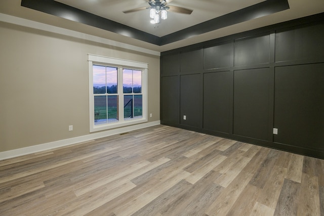 interior space with light hardwood / wood-style flooring, ceiling fan, and a raised ceiling