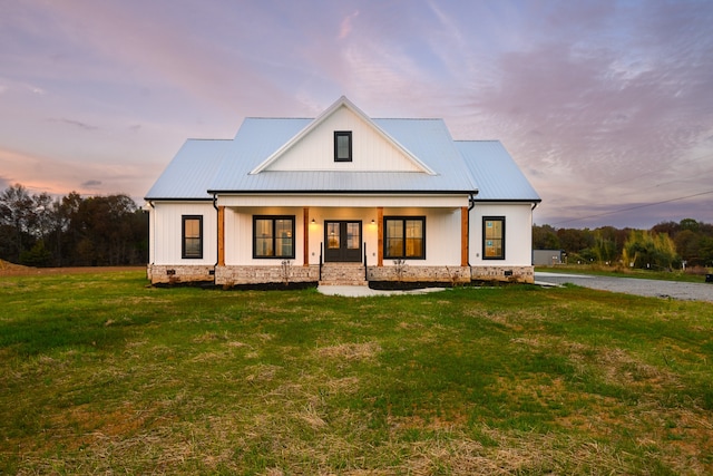 modern farmhouse style home featuring a lawn and covered porch