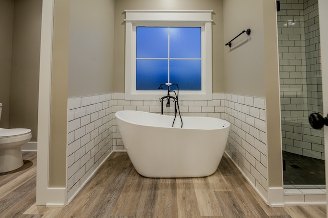 bathroom with tile walls, shower with separate bathtub, wood-type flooring, and toilet