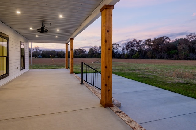 patio terrace at dusk featuring a lawn and ceiling fan