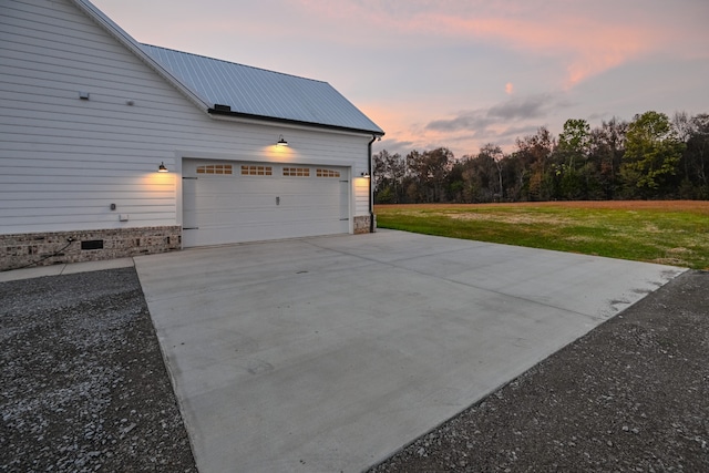 garage at dusk featuring a lawn