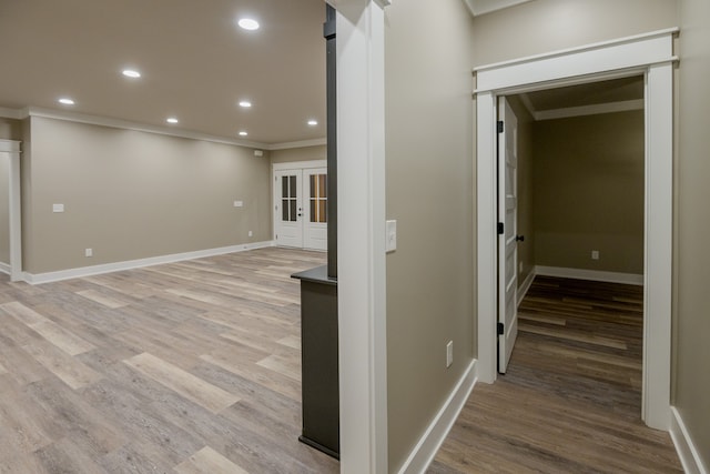 hallway featuring crown molding, light wood-type flooring, and french doors