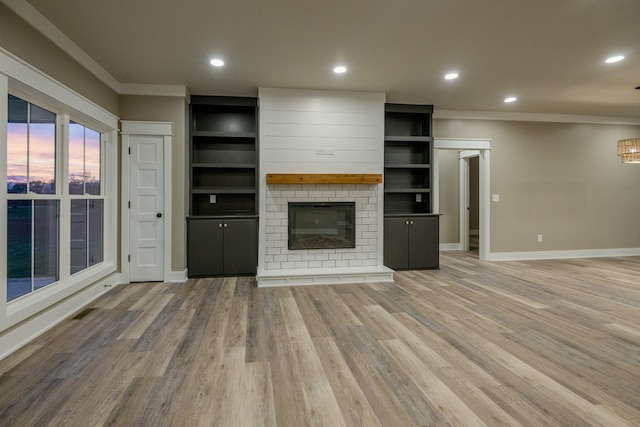 unfurnished living room with ornamental molding, light wood-type flooring, and a fireplace