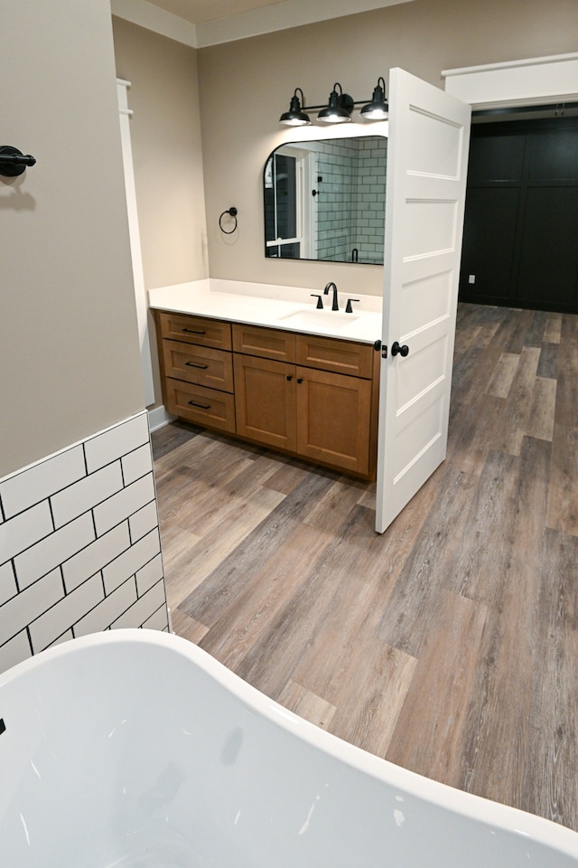 bathroom with a washtub, vanity, hardwood / wood-style floors, and crown molding