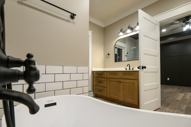 bathroom featuring a bathtub, wood-type flooring, crown molding, and vanity