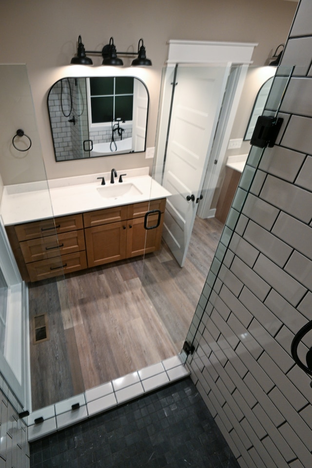 bathroom with walk in shower, vanity, and wood-type flooring