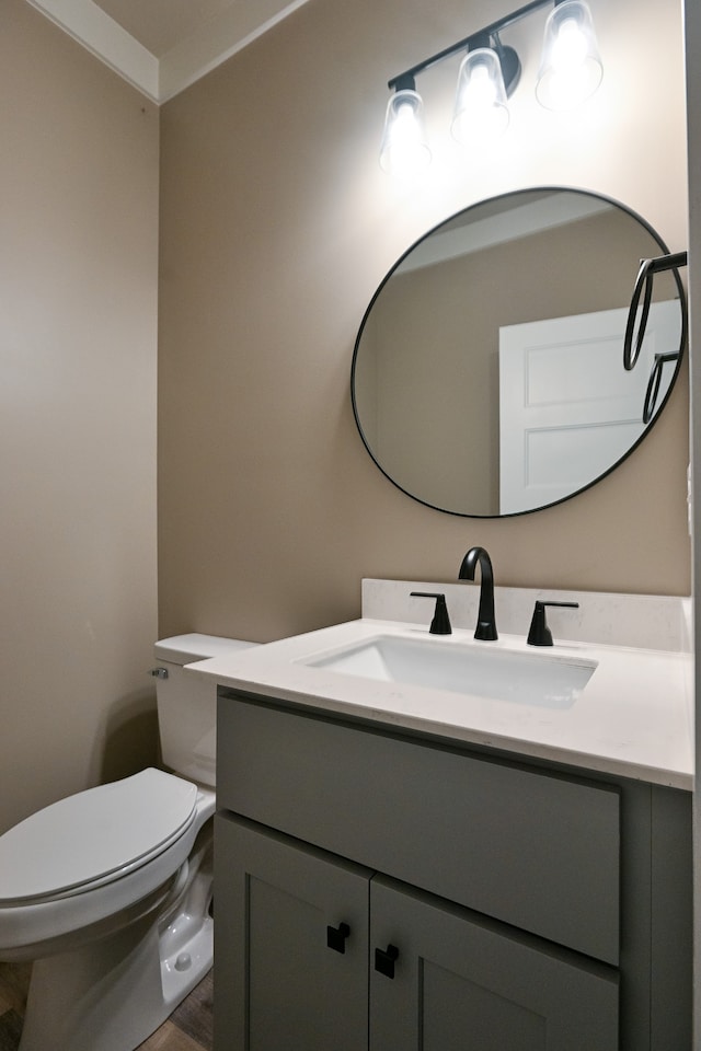 bathroom with hardwood / wood-style floors, vanity, toilet, and ornamental molding