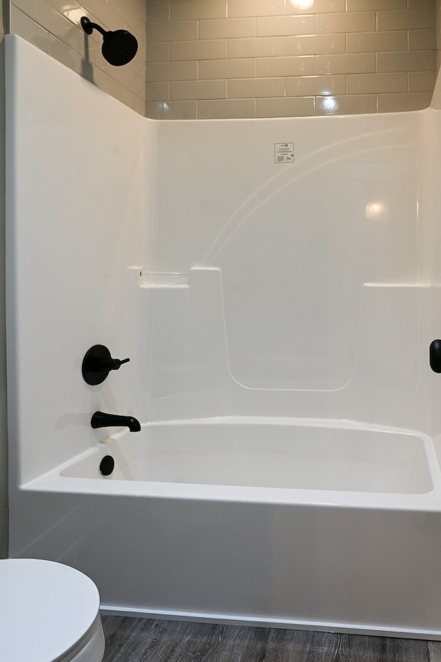 bathroom featuring wood-type flooring, toilet, and tiled shower / bath combo