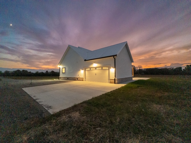 property exterior at dusk featuring a garage and a yard