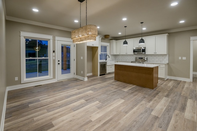 kitchen with stainless steel appliances, a center island, white cabinetry, light wood-type flooring, and decorative light fixtures