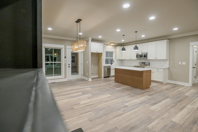 kitchen featuring white cabinets, appliances with stainless steel finishes, hanging light fixtures, and a kitchen island