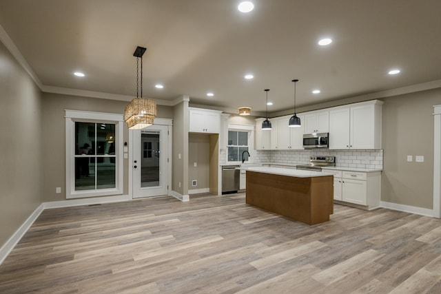 kitchen with a center island, white cabinets, light hardwood / wood-style flooring, hanging light fixtures, and appliances with stainless steel finishes