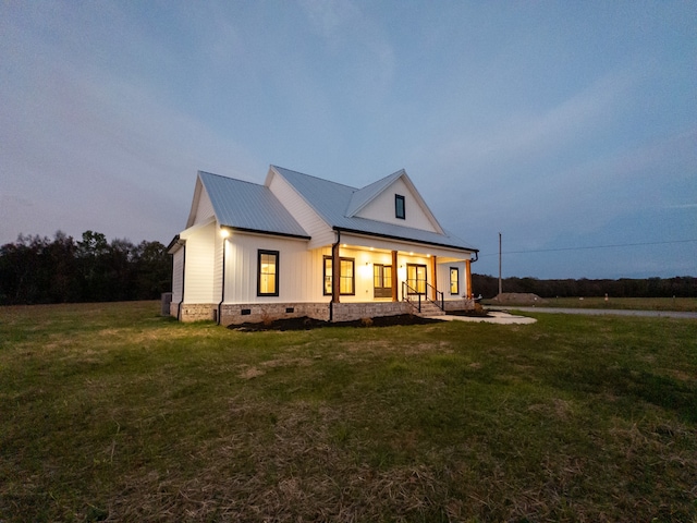 modern farmhouse style home with covered porch and a yard