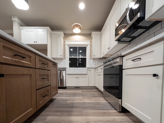 kitchen featuring white cabinets, light hardwood / wood-style floors, stainless steel appliances, and tasteful backsplash