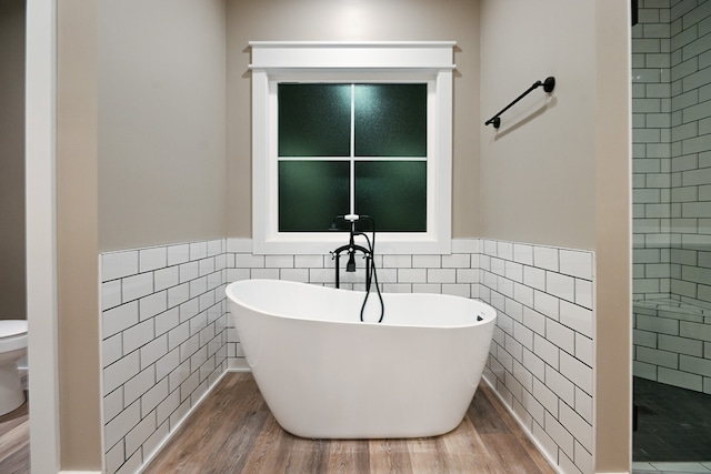 bathroom with hardwood / wood-style floors, independent shower and bath, toilet, and tile walls