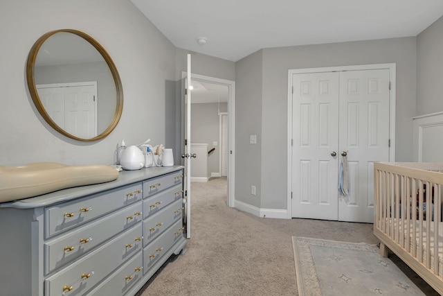 carpeted bedroom featuring a closet and a nursery area