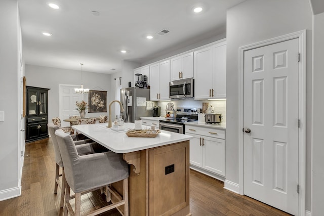 kitchen featuring white cabinets, an island with sink, stainless steel appliances, and dark hardwood / wood-style floors