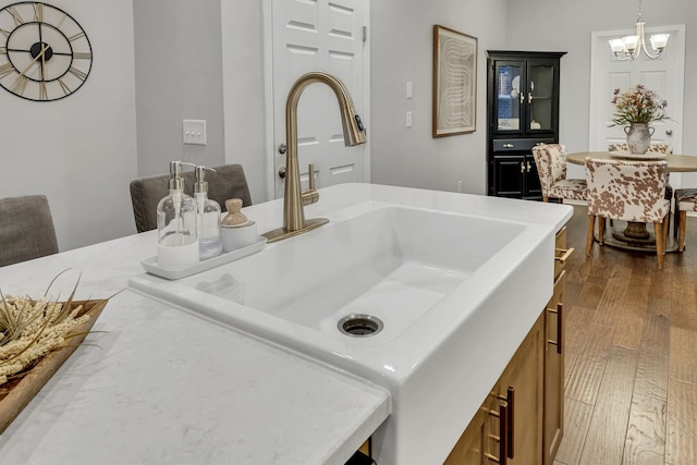 kitchen with sink, dark hardwood / wood-style flooring, hanging light fixtures, and an inviting chandelier