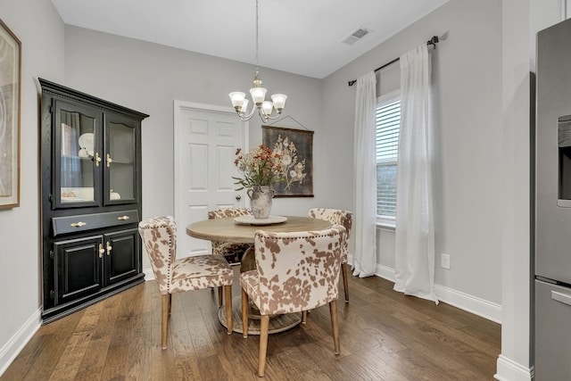 dining room with dark wood-type flooring and an inviting chandelier