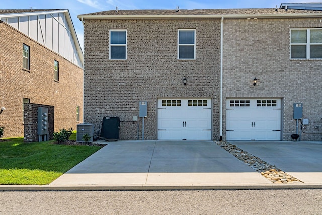 rear view of property featuring central AC unit and a garage