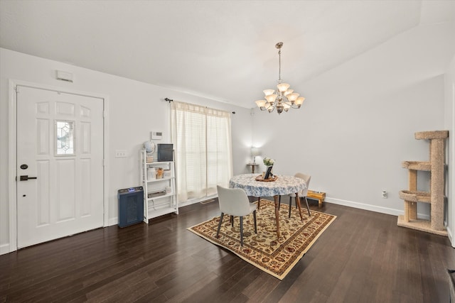 dining area with dark wood-type flooring, vaulted ceiling, and a chandelier