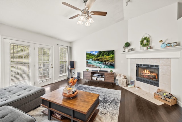 living room featuring a tiled fireplace, vaulted ceiling, hardwood / wood-style flooring, and ceiling fan