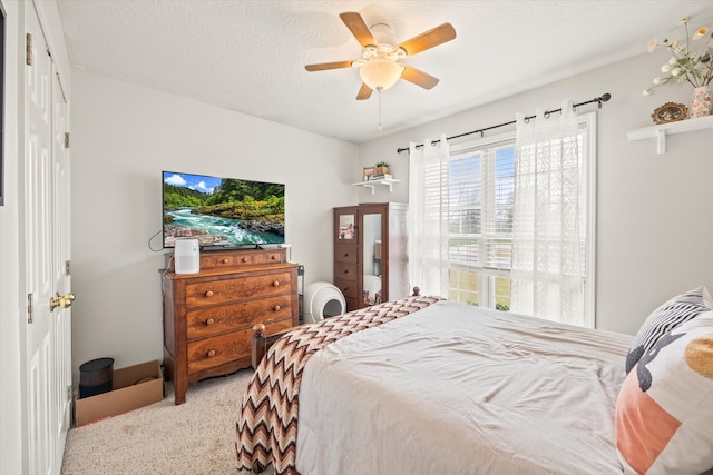 bedroom with light colored carpet, a textured ceiling, and ceiling fan