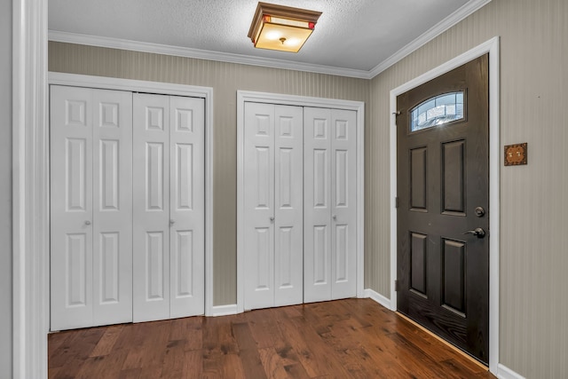 foyer featuring dark hardwood / wood-style floors, crown molding, and a textured ceiling