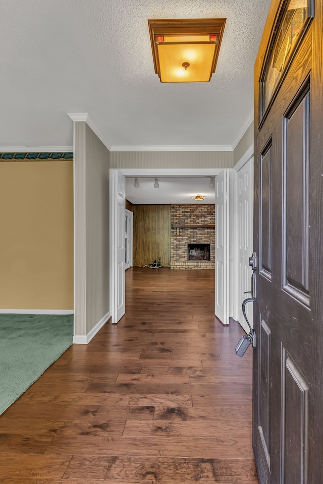 entryway featuring a brick fireplace, crown molding, dark hardwood / wood-style flooring, and a textured ceiling