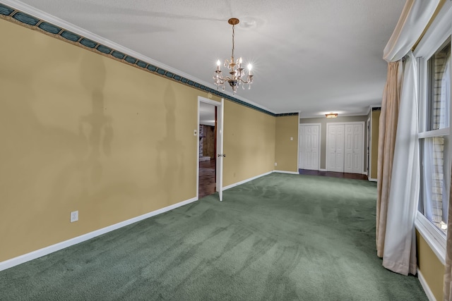 unfurnished room featuring crown molding, dark carpet, and an inviting chandelier