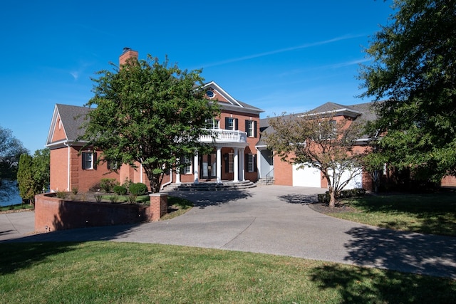 view of front facade with a balcony, a garage, and a front lawn