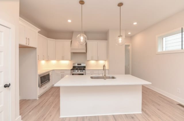 kitchen with appliances with stainless steel finishes, a kitchen island with sink, sink, and white cabinets