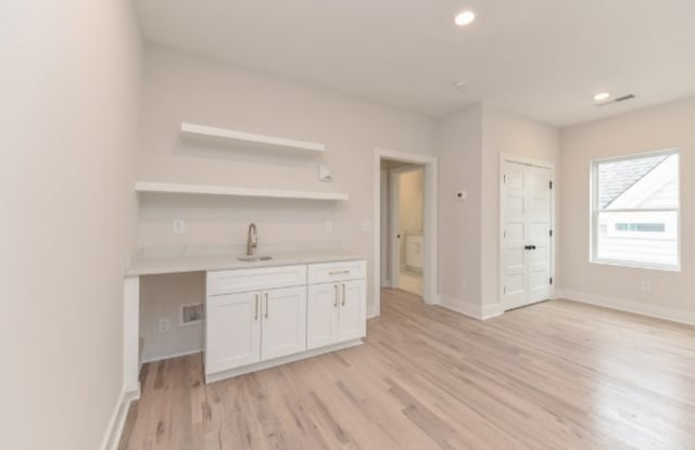 kitchen with light wood-type flooring, sink, and white cabinets